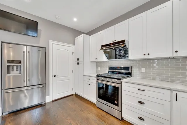 a kitchen with stainless steel appliances white cabinets and a stove top oven