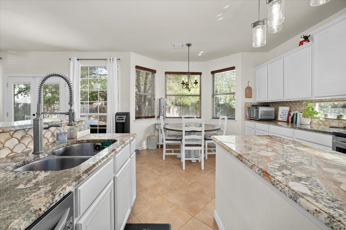 455 Logan Road Georgetown, TX 78628 - Photo 12 of 35 a large kitchen with kitchen island a large counter top space a sink stainless steel appliances and windows
