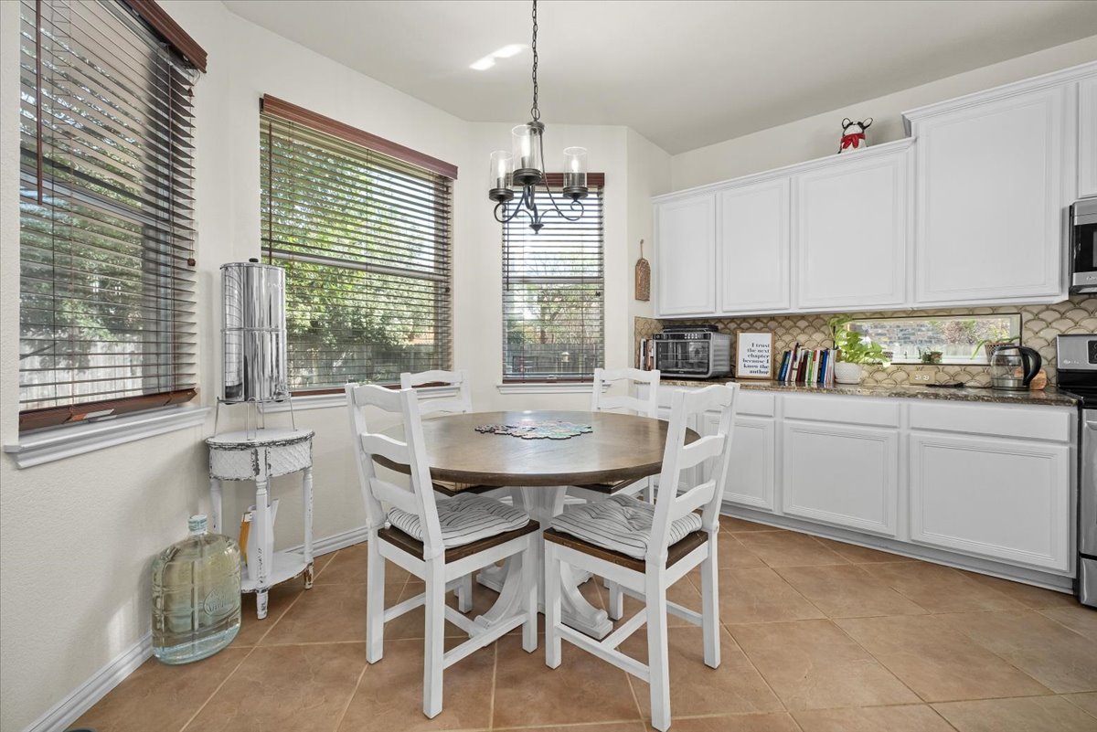 455 Logan Road Georgetown, TX 78628 - Photo 13 of 35 a kitchen with a dining table chairs and large windows