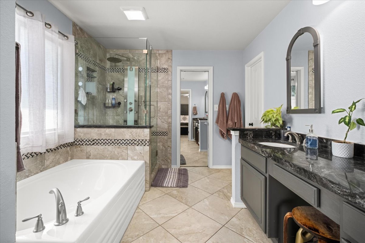 455 Logan Road Georgetown, TX 78628 - Photo 18 of 35 a spacious bathroom with a granite countertop tub sink and mirror