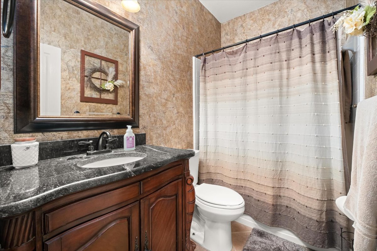 455 Logan Road Georgetown, TX 78628 - Photo 28 of 35 a bathroom with a granite countertop sink a toilet and a mirror
