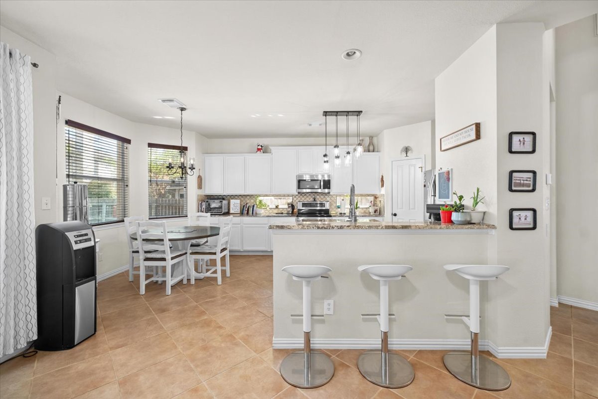 455 Logan Road Georgetown, TX 78628 - Photo 10 of 35 a kitchen with stainless steel appliances kitchen island granite countertop a table and chairs in it