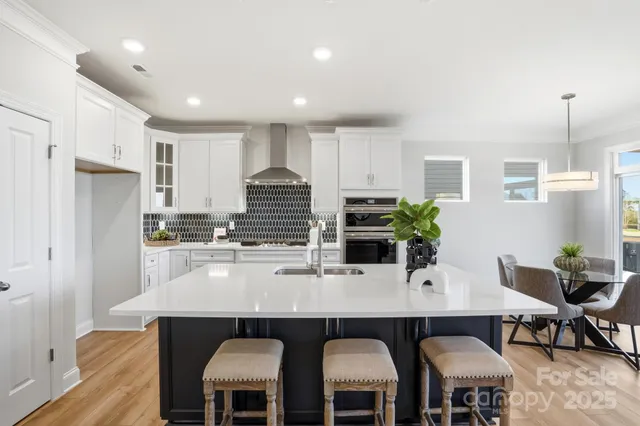 a kitchen with stainless steel appliances a dining table chairs and refrigerator