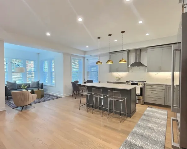 a kitchen with kitchen island granite countertop a table chairs sink and refrigerator