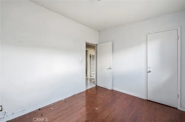 a view of an empty room with wooden floor and closet