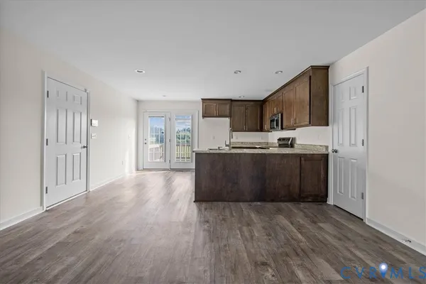 a view of a livingroom with wooden floor and a kitchen