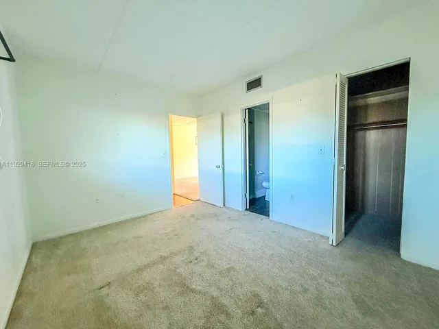 an empty room with closet and a bathroom