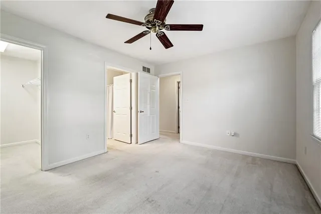 an empty room with ceiling fan and window