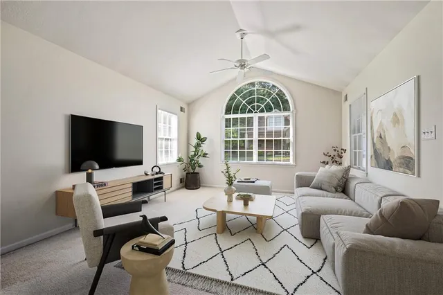 a living room with furniture a flat screen tv and a large window