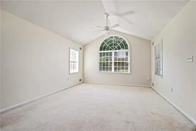 an empty room with a ceiling fan and windows