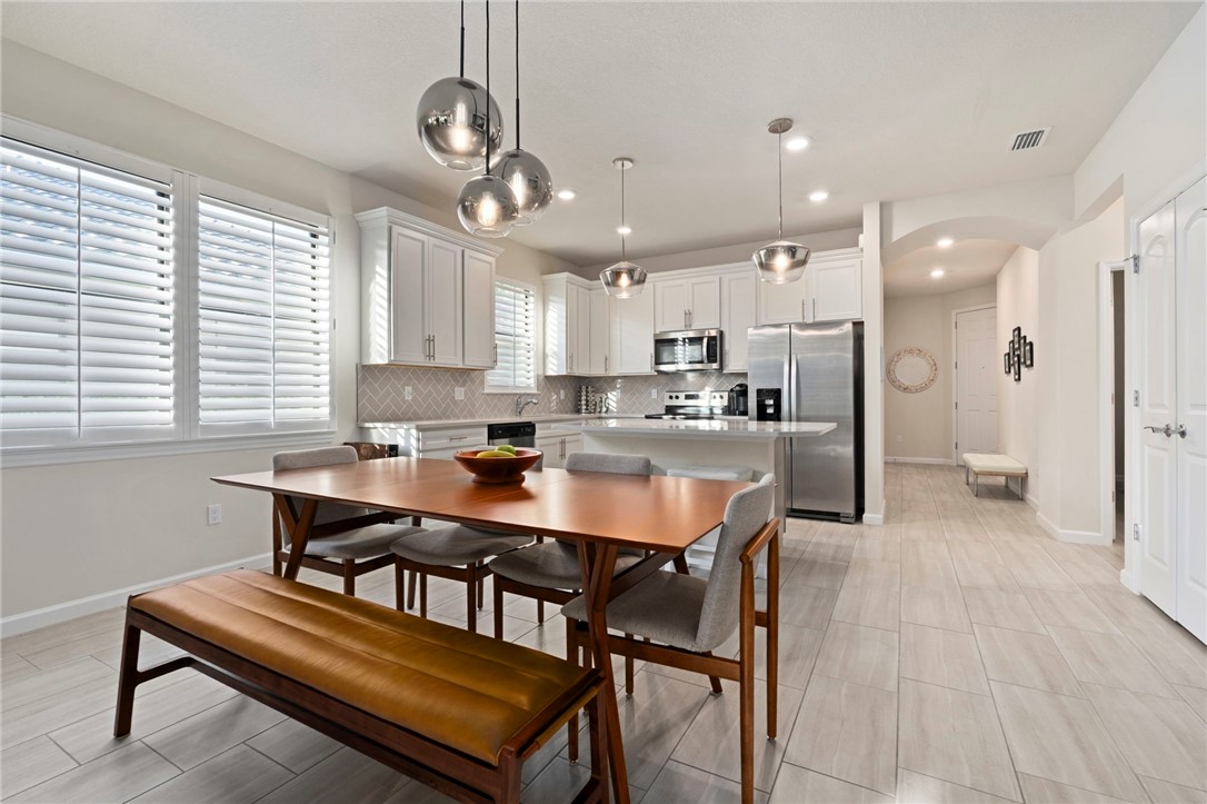 5208 Unity Square Vero Beach, FL 32967 - Photo 13 of 34 a kitchen with kitchen island a dining table chairs and a refrigerator