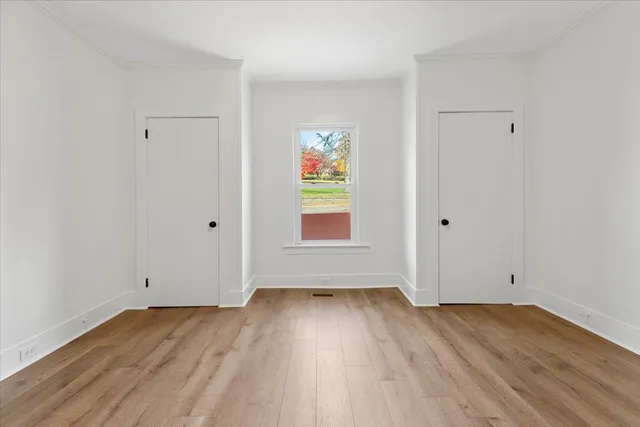 an empty room with wooden floor and window