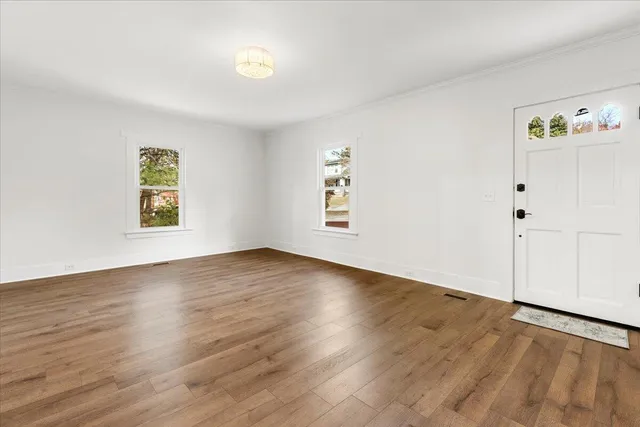 an empty room with wooden floor and window