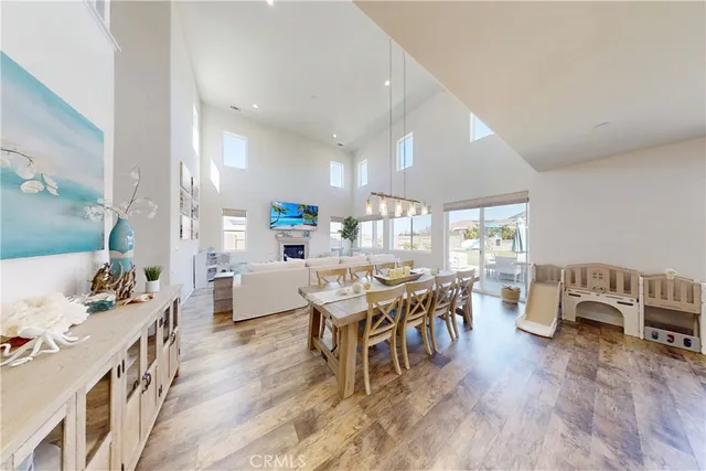 a kitchen with stainless steel appliances granite countertop a refrigerator a sink dishwasher a stove a dining table and chairs with wooden floor