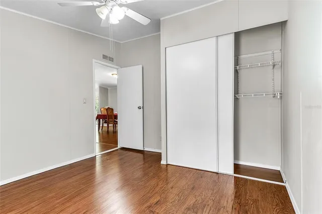 an empty room with wooden floor and a ceiling fan