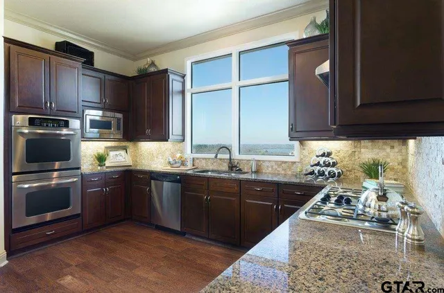 a kitchen with stainless steel appliances granite countertop a sink stove and refrigerator