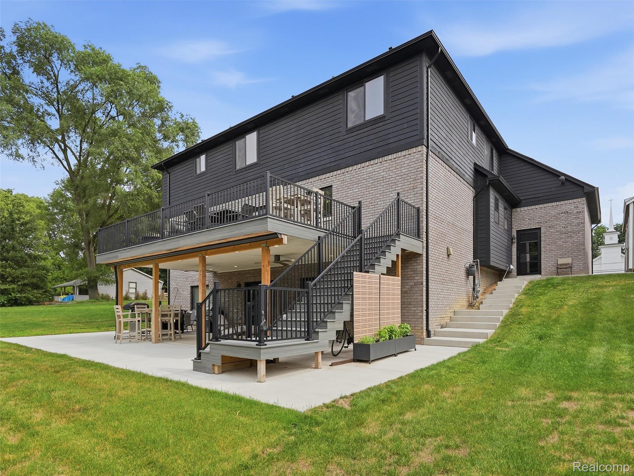 3007 28 Mile Road Washington, MI 48094 - Photo 56 of 69 Multi-level outdoor living space featuring a second-story deck with black metal railing, a covered patio with wood support beams, and a concrete paver patio