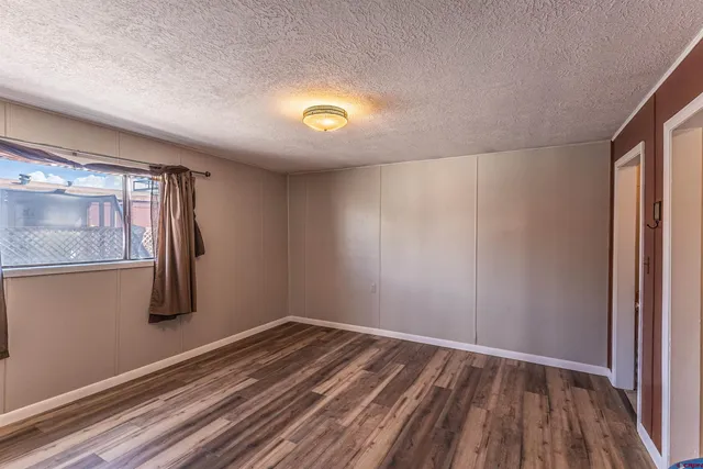a view of an empty room with closet and wooden floor