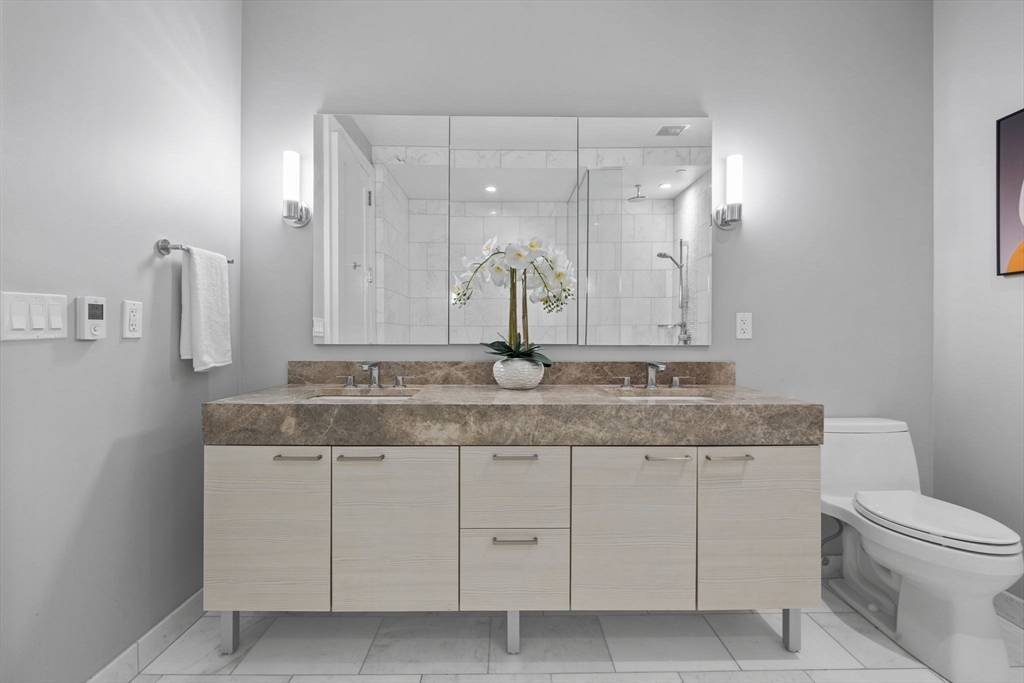 1 Franklin Street, Unit 3808 Boston, MA 02110 - Photo 19 of 40 a bathroom with a granite countertop sink a toilet and a mirror