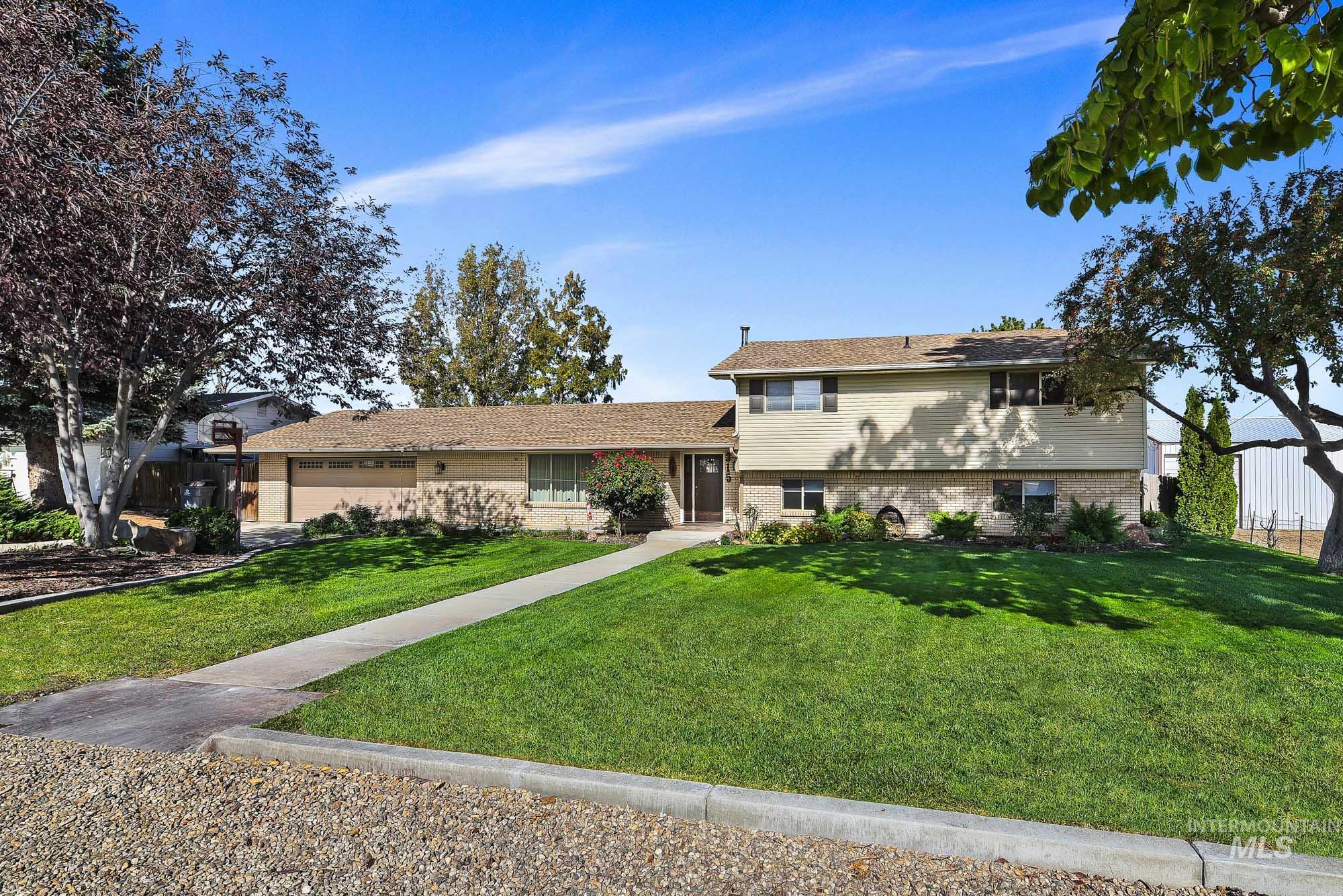 315 East Pat Lane Caldwell, ID 83607 - Photo 1 of 50 Tri-level home featuring brick accents and vinyl siding, a plush front yard, and an attached 2 car garage
