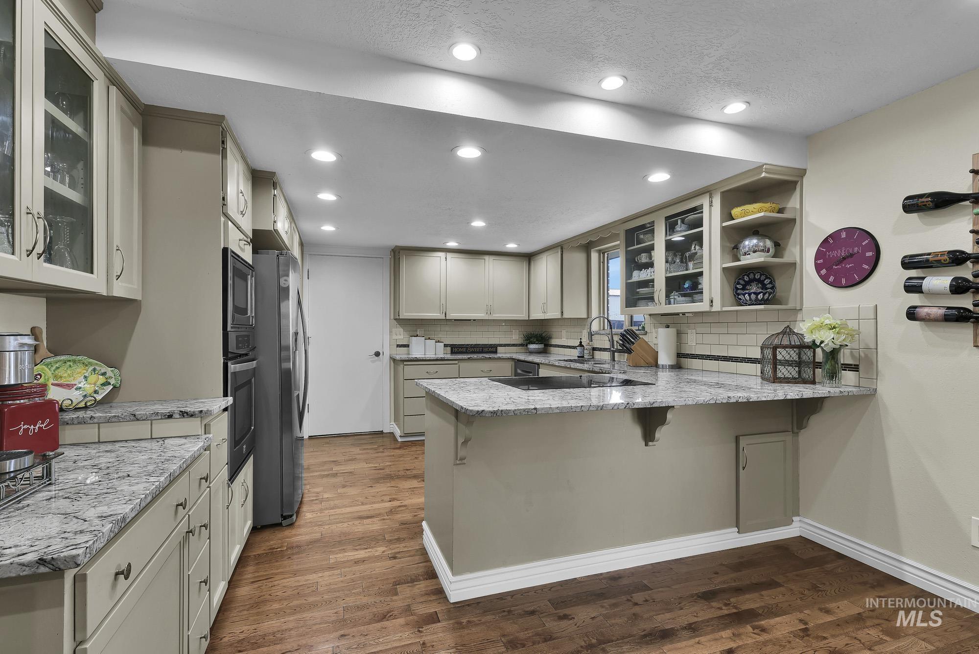 315 East Pat Lane Caldwell, ID 83607 - Photo 13 of 50 Kitchen featuring glass insert cabinets, light granite countertops, a peninsula, a kitchen breakfast bar, and recessed lighting