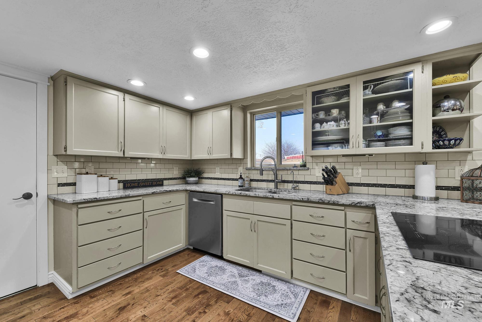 315 East Pat Lane Caldwell, ID 83607 - Photo 14 of 50 Kitchen featuring light granite countertops, recessed lighting, glass insert cabinets, stainless steel dishwasher, and black induction stovetop