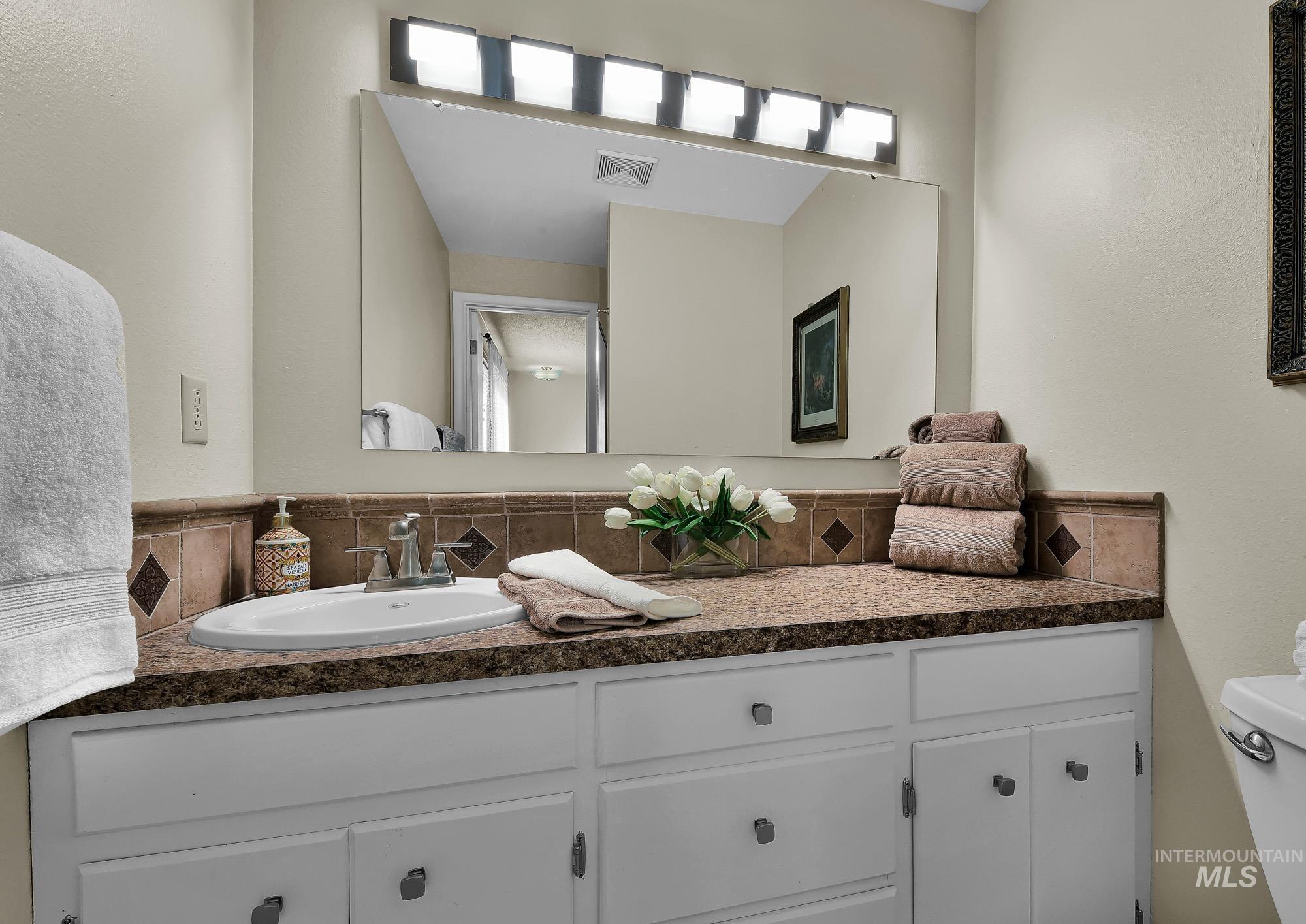 315 East Pat Lane Caldwell, ID 83607 - Photo 38 of 50 Primary Bathroom featuring large vanity, tile backsplash and oversized mirror with newer lighting