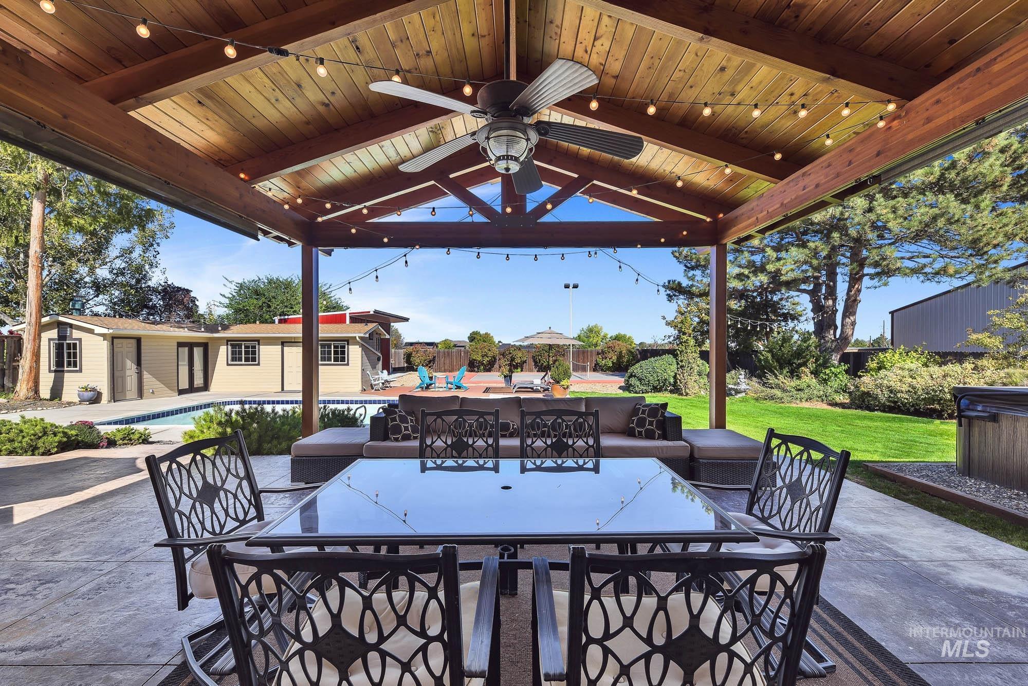 315 East Pat Lane Caldwell, ID 83607 - Photo 41 of 50 View of patio featuring outdoor dining area, a ceiling fan, an outdoor pool, an outdoor pool building and a pickleball court