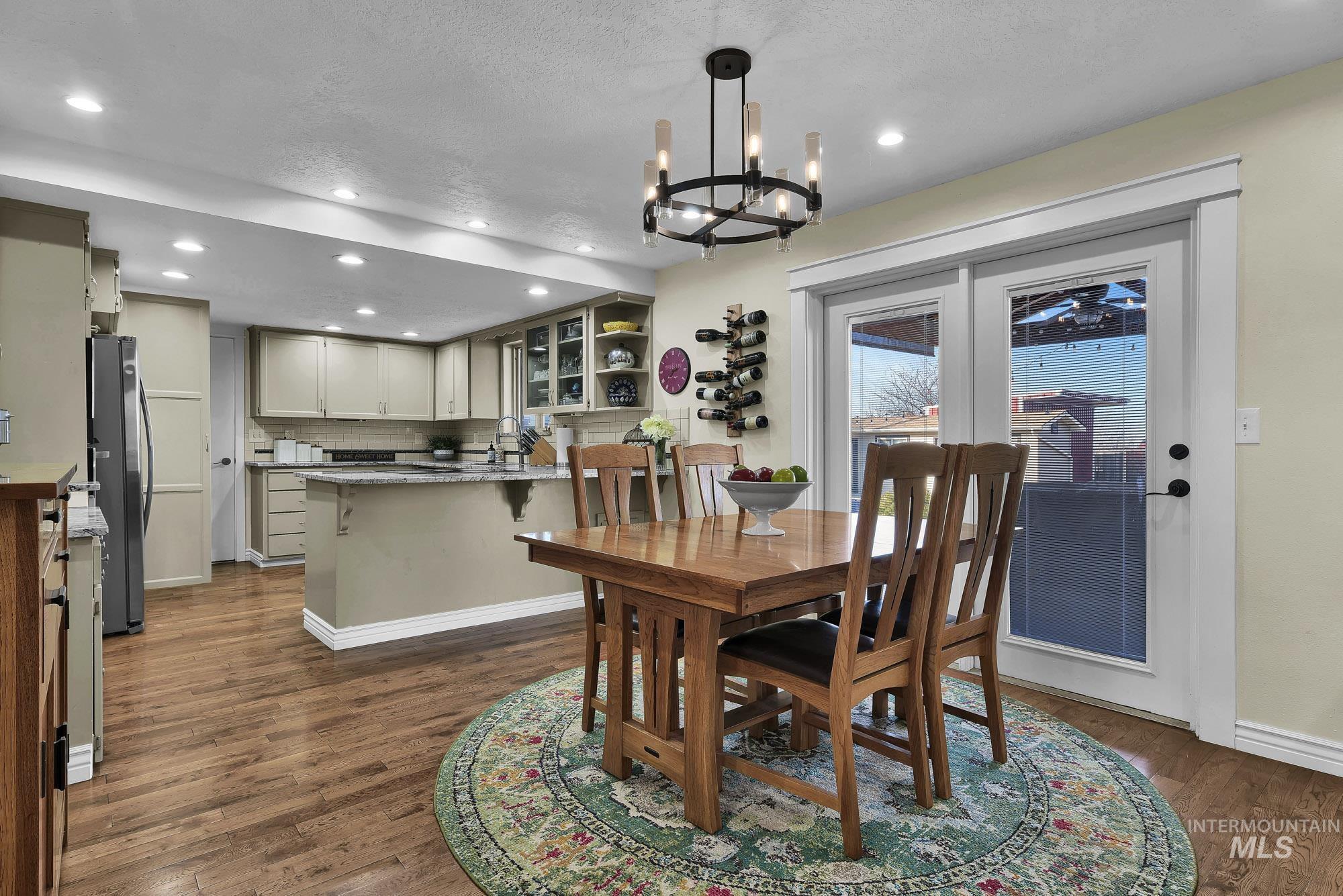 315 East Pat Lane Caldwell, ID 83607 - Photo 10 of 50 Dining area featuring a chandelier, recessed lighting, hardwood flooring - open to the kitchen and access to the breakfast bar and back covered patio