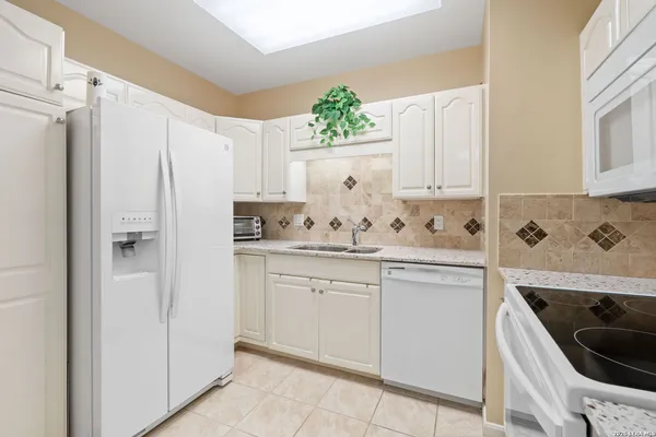 a kitchen with granite countertop white cabinets and white appliances