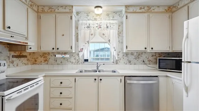a view of a kitchen with a sink and dishwasher a refrigerator with wooden floor