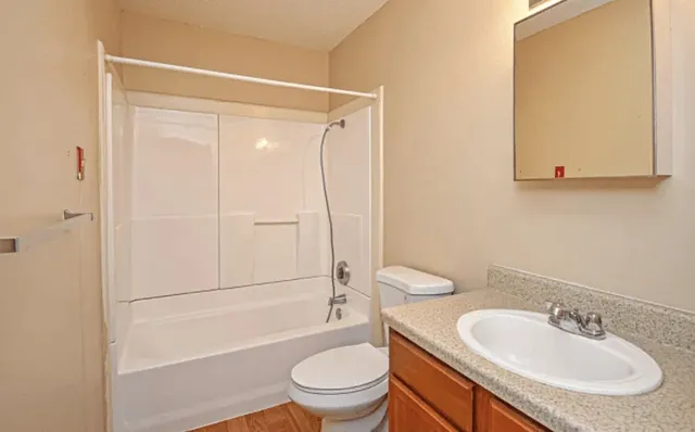 a bathroom with a granite countertop sink toilet and shower