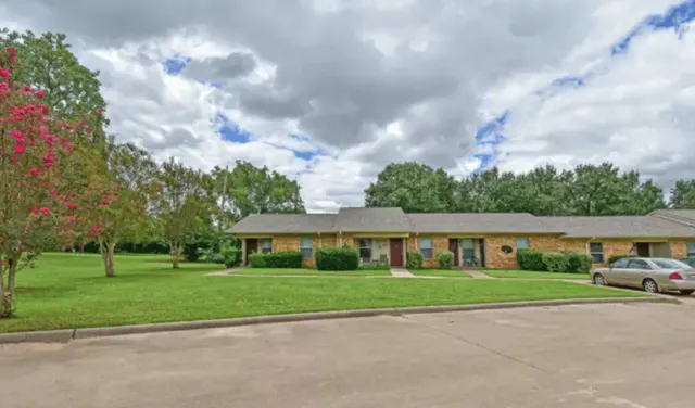 a view of house with a big yard and large trees