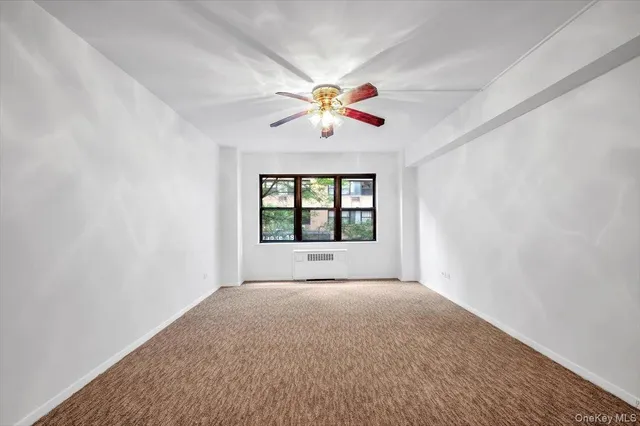 a view of an empty room with window and a kitchen