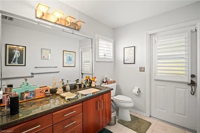 a spacious bathroom with a granite countertop sink a toilet and a mirror