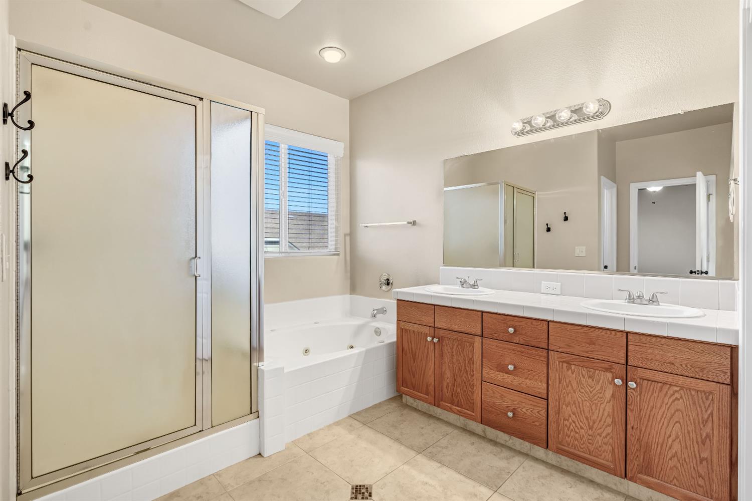 5629 North Citrus Lane Fresno, CA 93711 - Photo 19 of 35 a spacious bathroom with a double vanity sink a large mirror and a bathtub