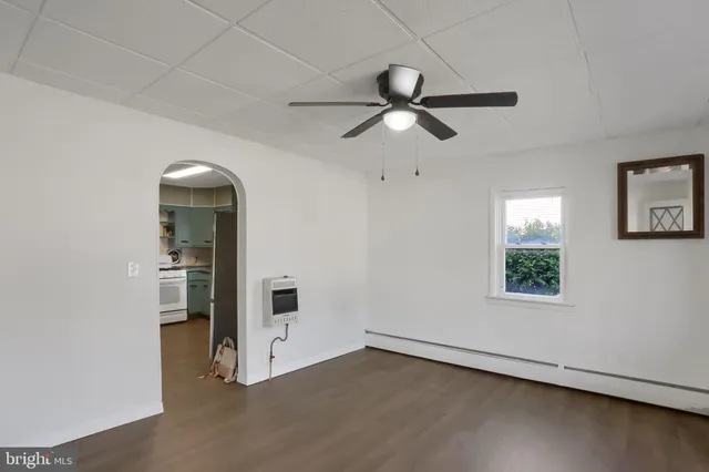 an empty room with wooden floor closet and windows