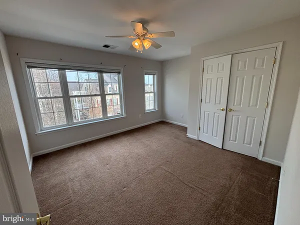 an empty room with chandelier fan and windows