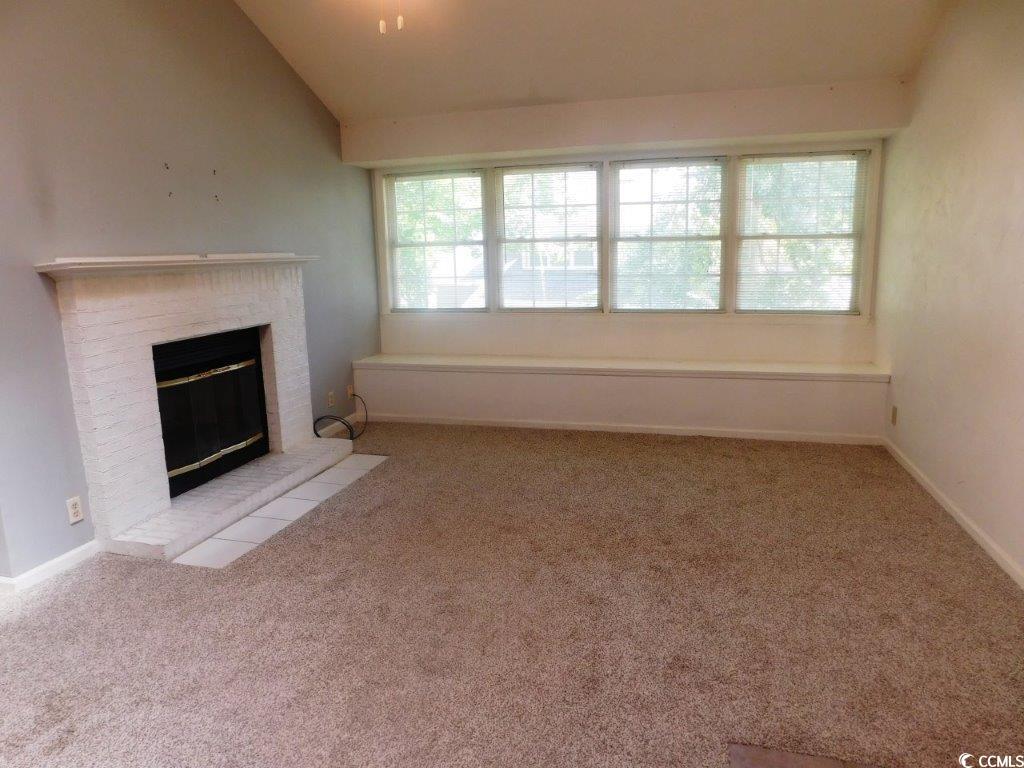 1202 Tiffany Lane, Unit D Myrtle Beach, SC 29577 - Photo 4 of 21 Unfurnished living room featuring plenty of natural light, carpet flooring, a fireplace, and lofted ceiling
