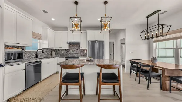 a kitchen with stainless steel appliances kitchen island granite countertop a table chairs and a stove