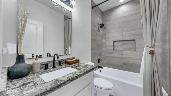 a bathroom with a granite countertop tub sink toilet and a mirror