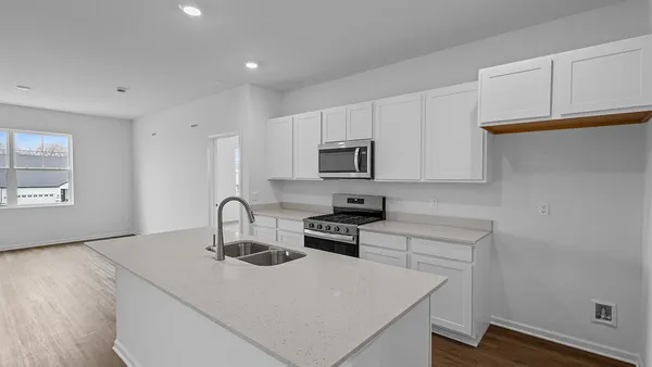 a kitchen with sink a microwave a stove and cabinets