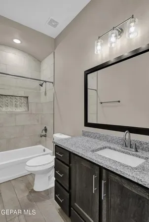 a bathroom with a granite countertop sink a toilet a mirror and bathtub