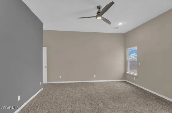 an empty room with windows and fan