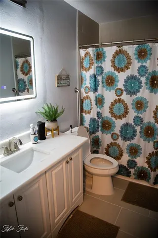 a bathroom with a sink a toilet and shower curtain