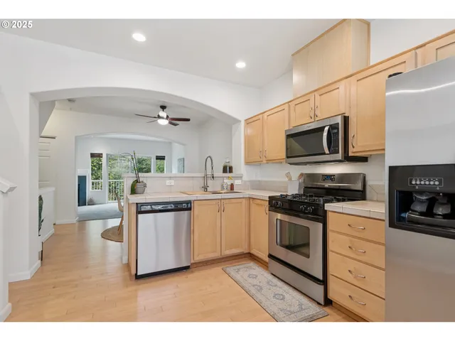 a kitchen with stainless steel appliances granite countertop a sink a stove top oven a chimney a counter space and cabinets