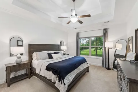 a bedroom with a bed large window and a chandelier