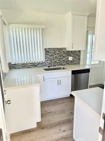 a kitchen with a sink a stove cabinets and wooden floor