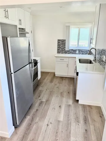 a kitchen with a refrigerator a sink and dishwasher with wooden floor