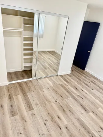 a view of an empty room with wooden floor and closet